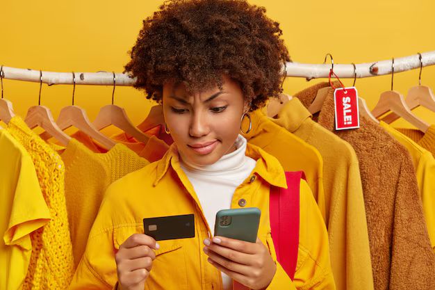 Une femme afro sérieuse utilise une carte de crédit avec un téléphone portable